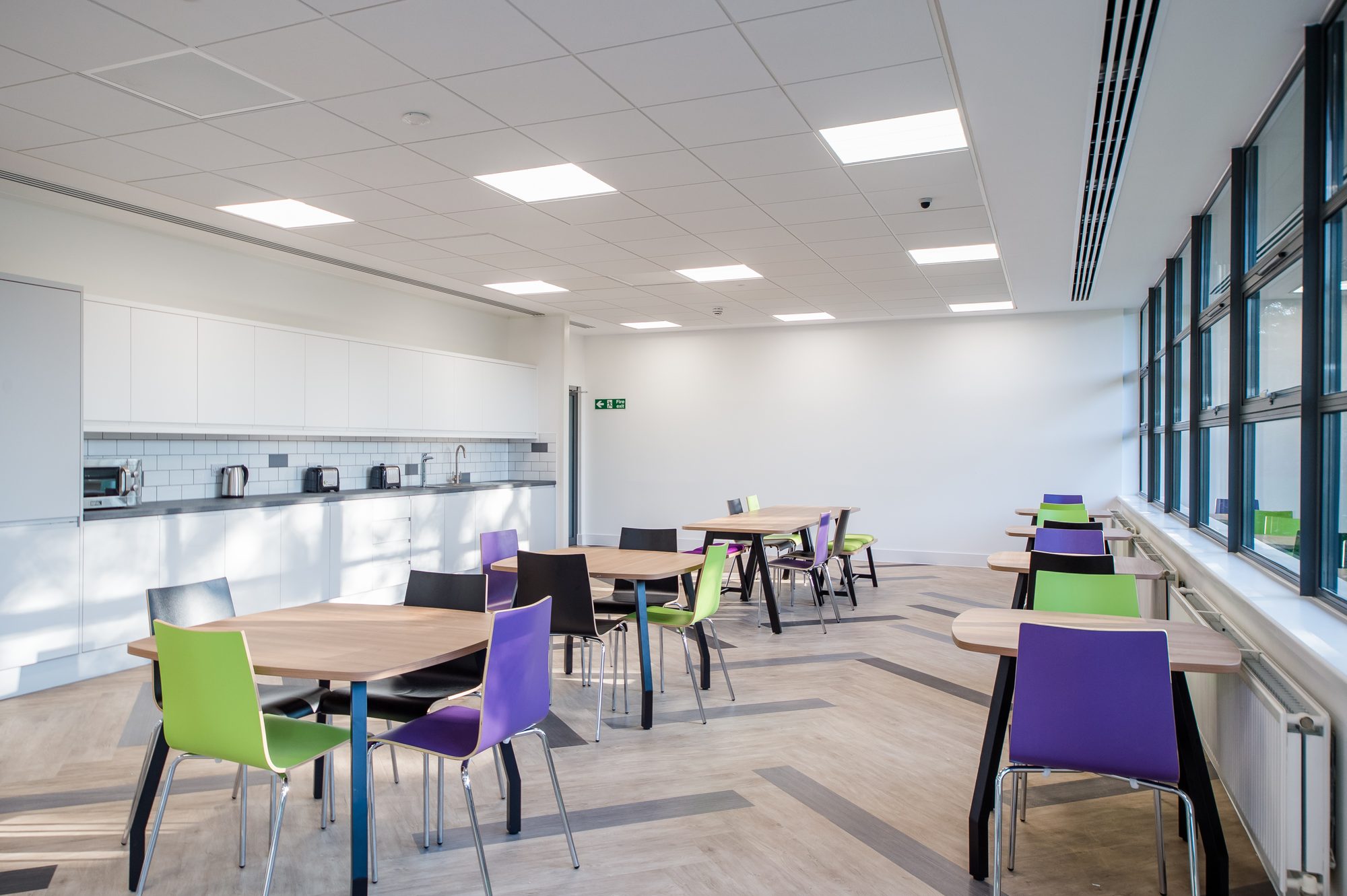 Staff café and kitchen with timber tables and accent chairs