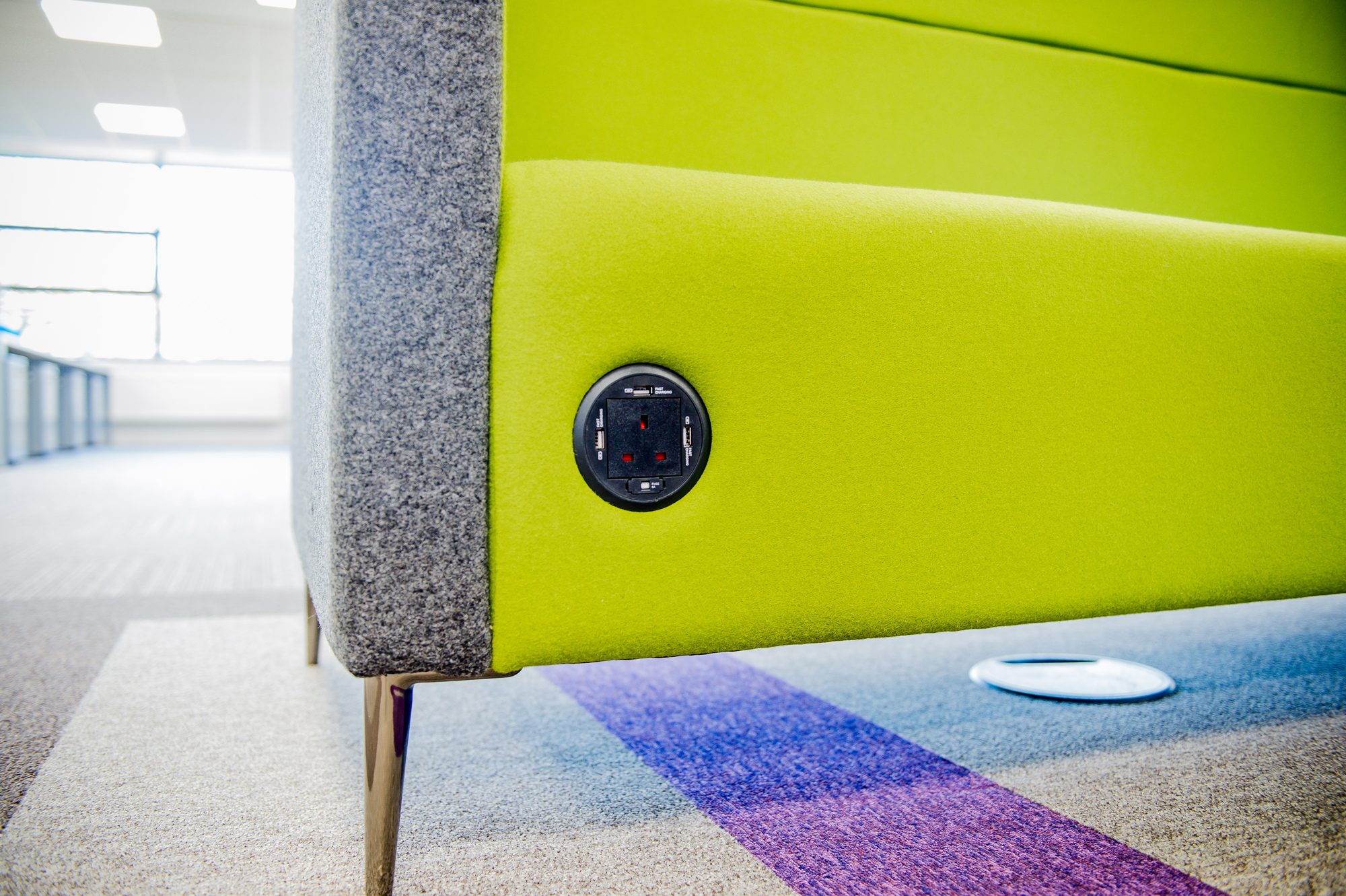 Integrated power and USB sockets built into a green acoustic sofa