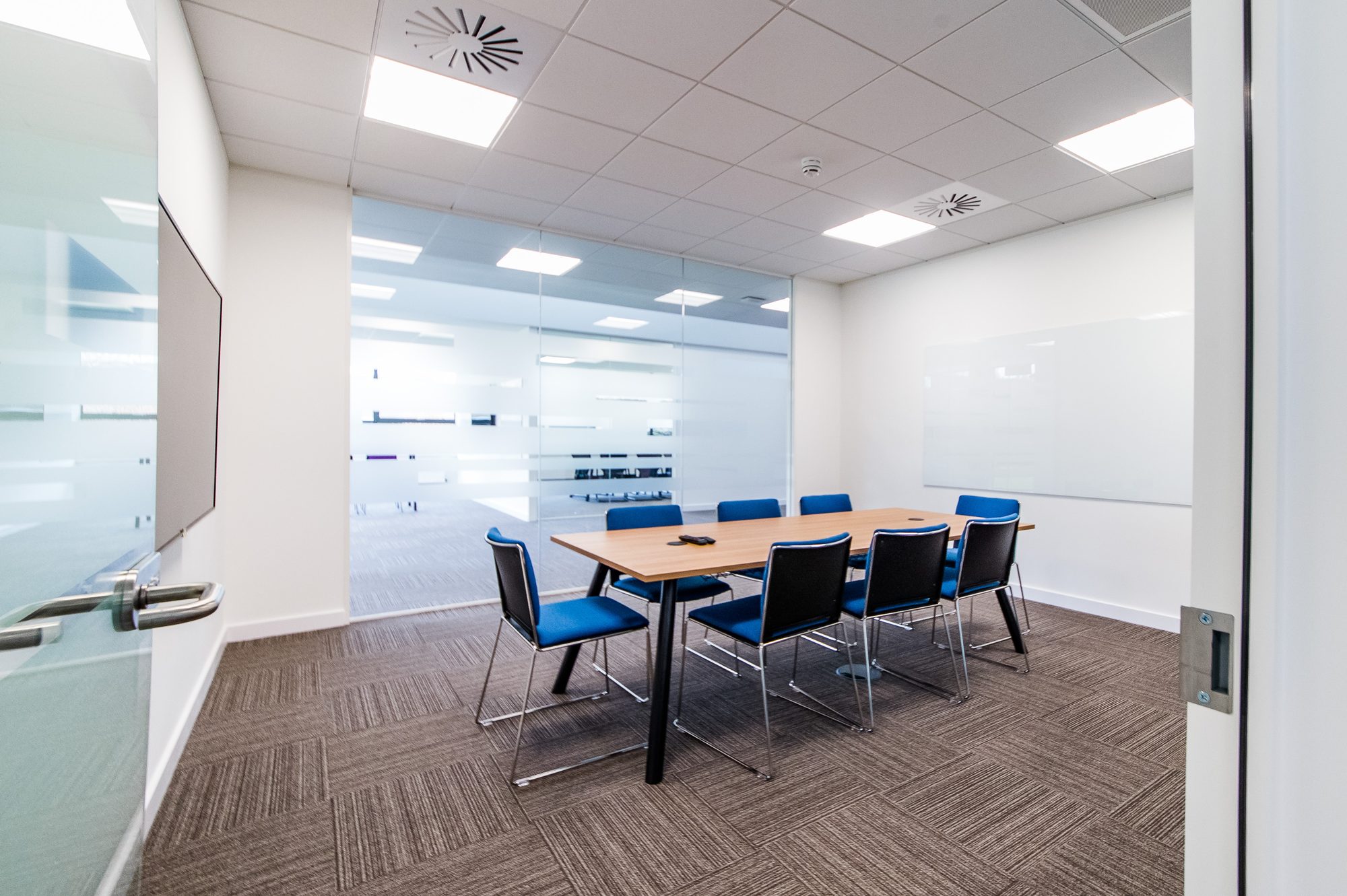 Smaller breakout meeting room with blue chairs and writeable wall