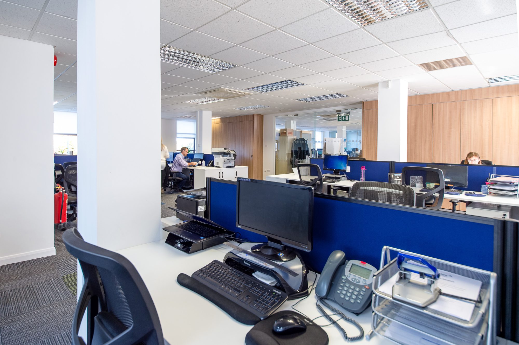Close-up of a working desk with monitor, phone and acoustic screen