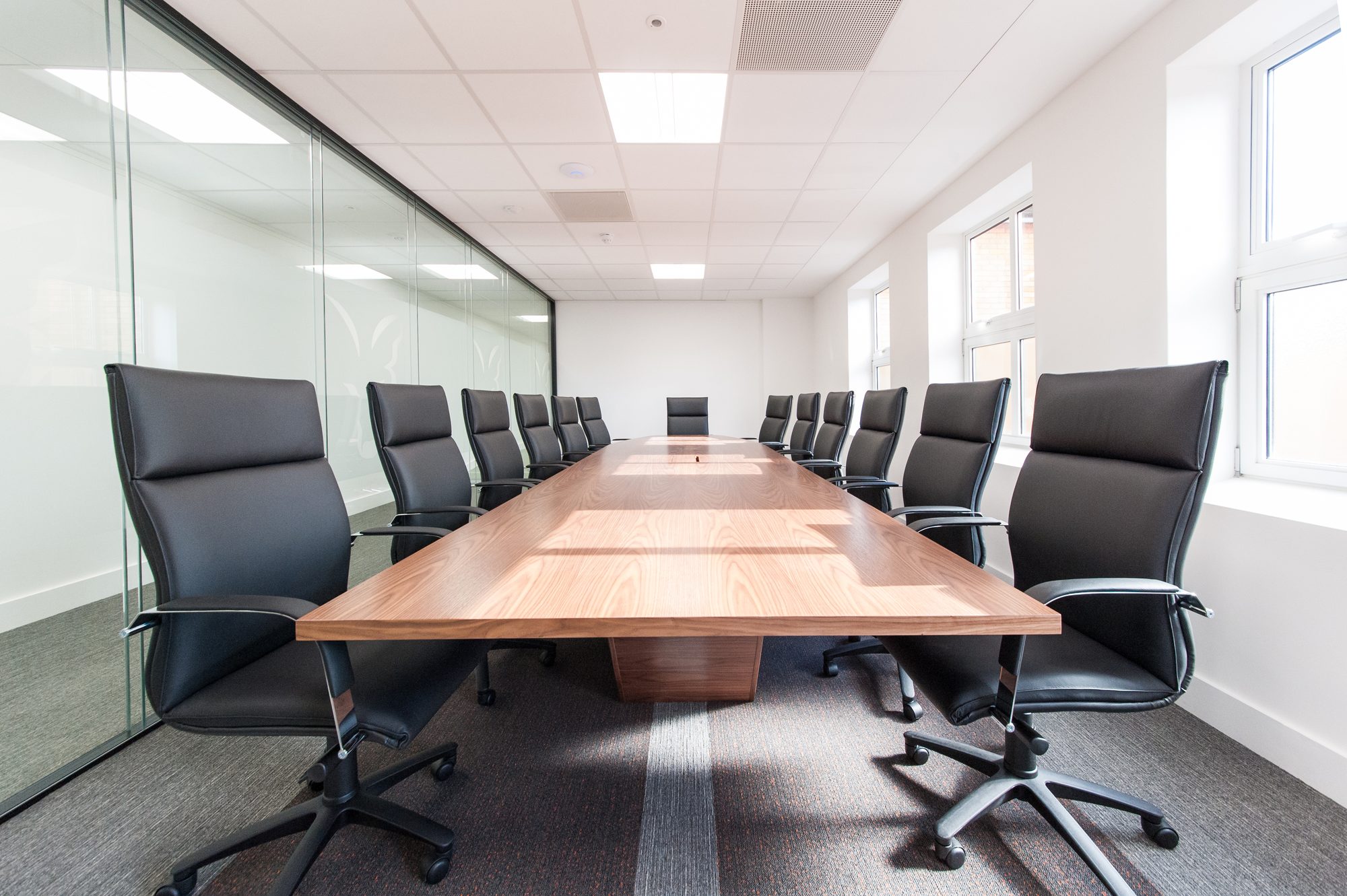 Executive boardroom with bespoke walnut table and black leather chairs