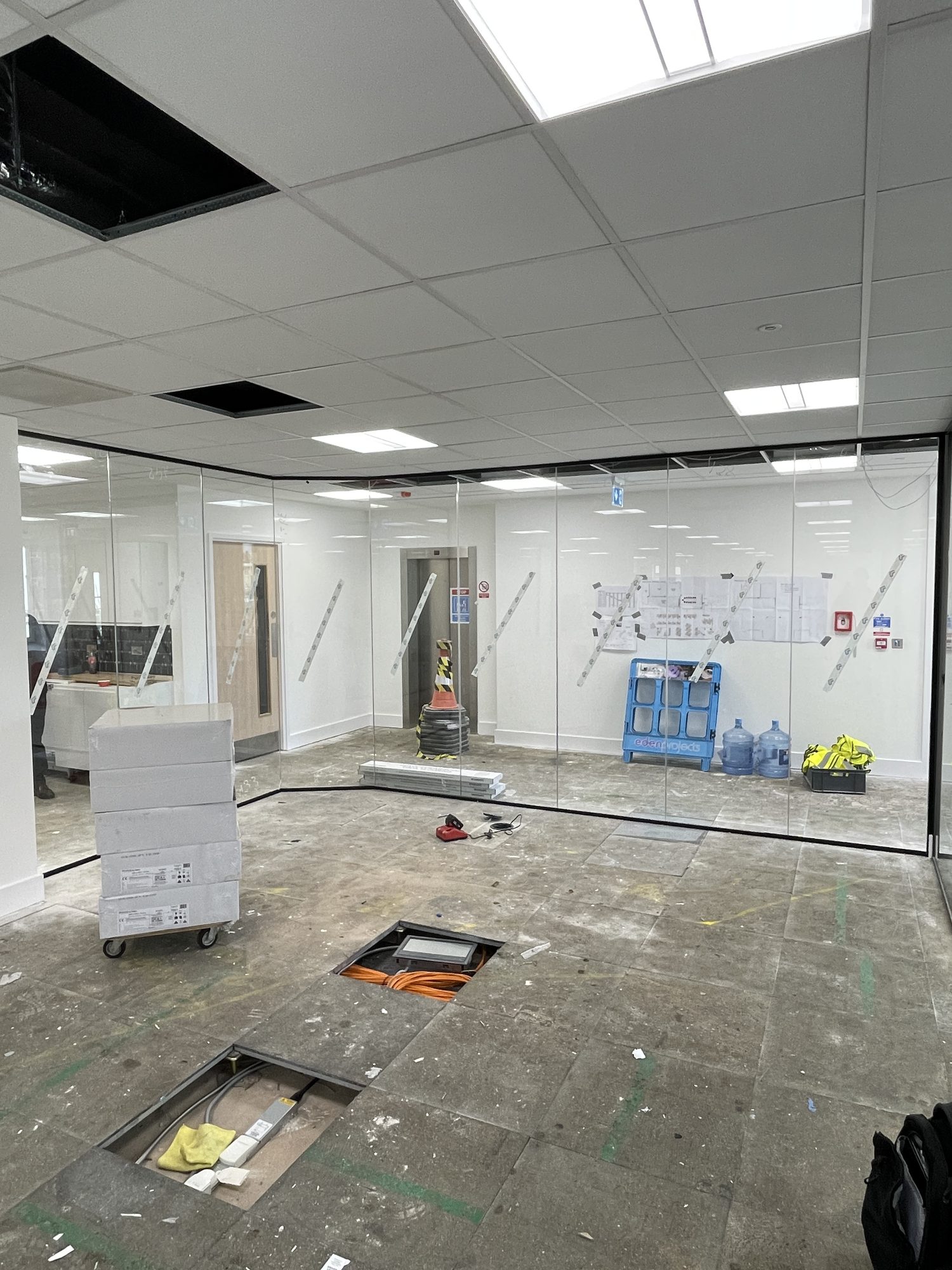 Glazed meeting room with floor tiles up for final services