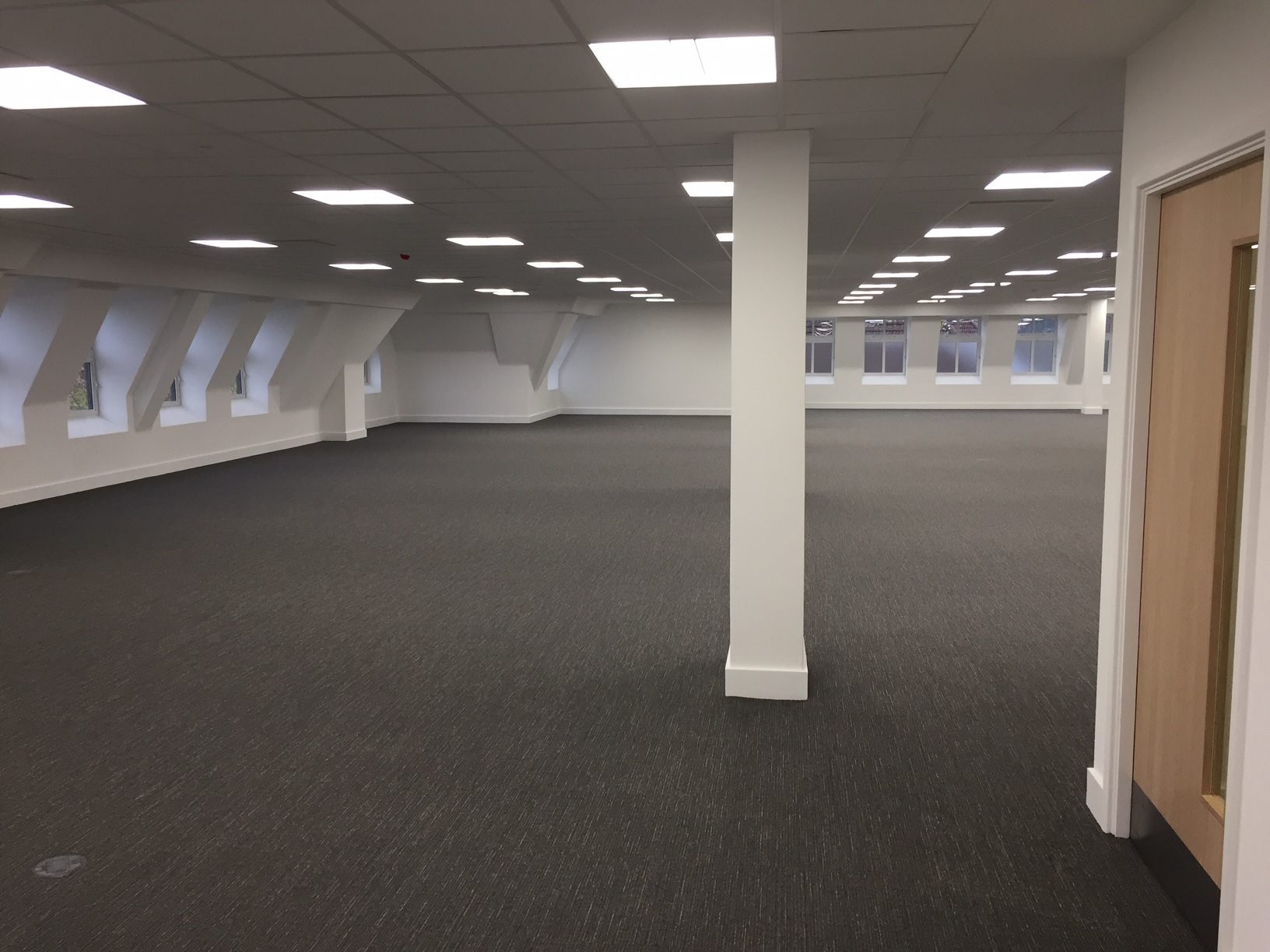 Empty second floor from the opposite end, showing dormer windows