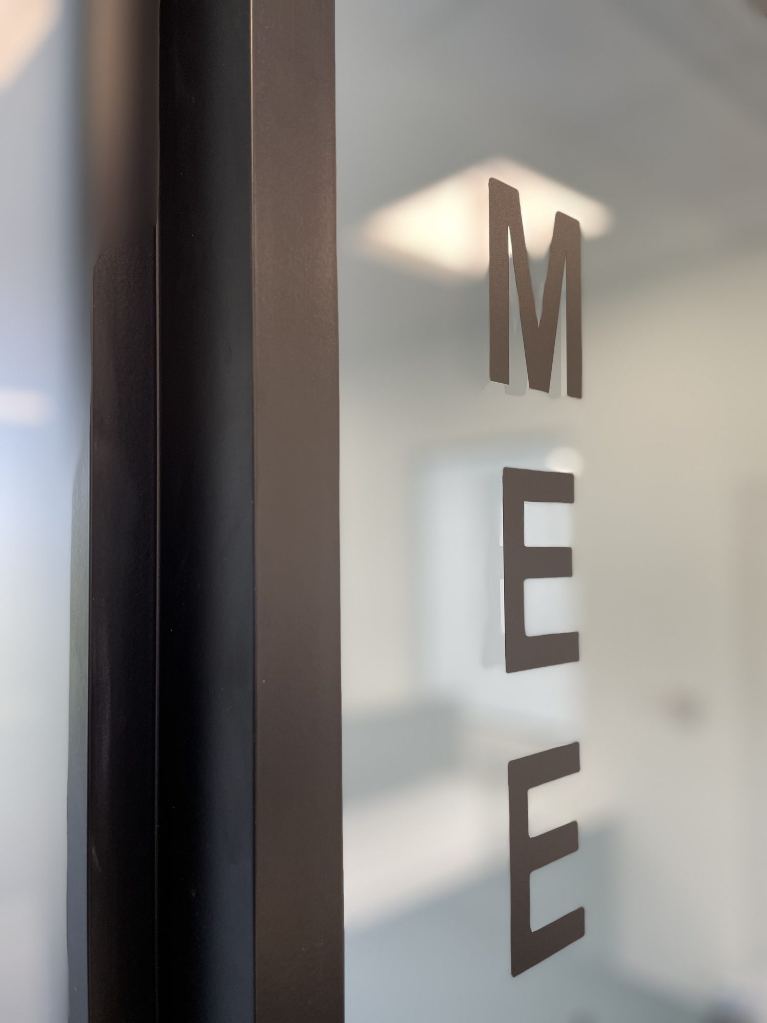 Close-up of the frosted glass manifestation lettering on a meeting room door