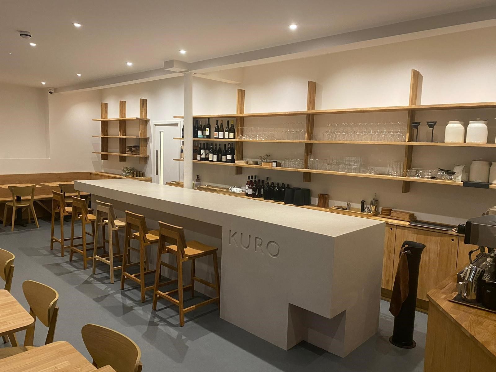 Wider angle of the bar showing oak shelving and wine display