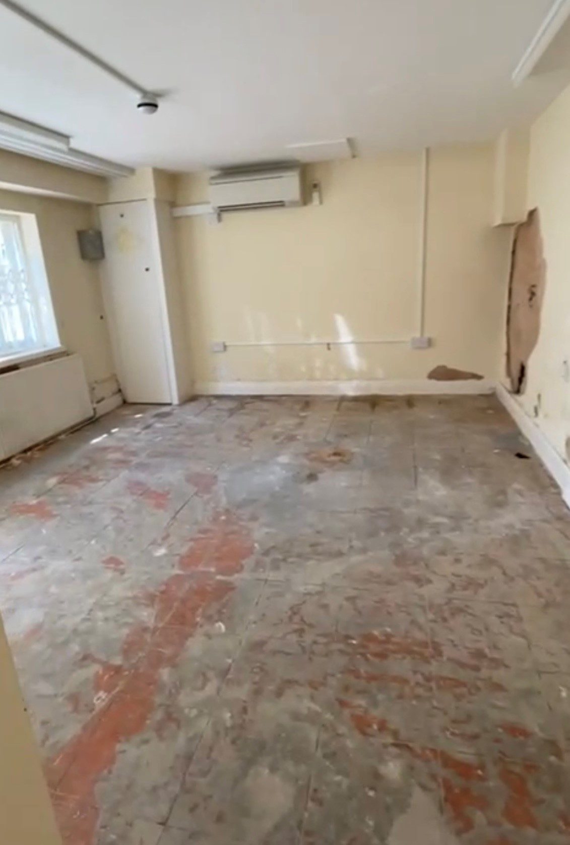Empty bank unit before fit-out, with yellow walls and cracked tile floor