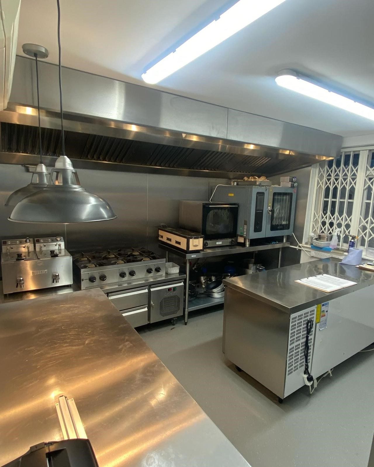Stainless steel commercial kitchen with extraction, six-burner range, fryer, combi oven and salamander