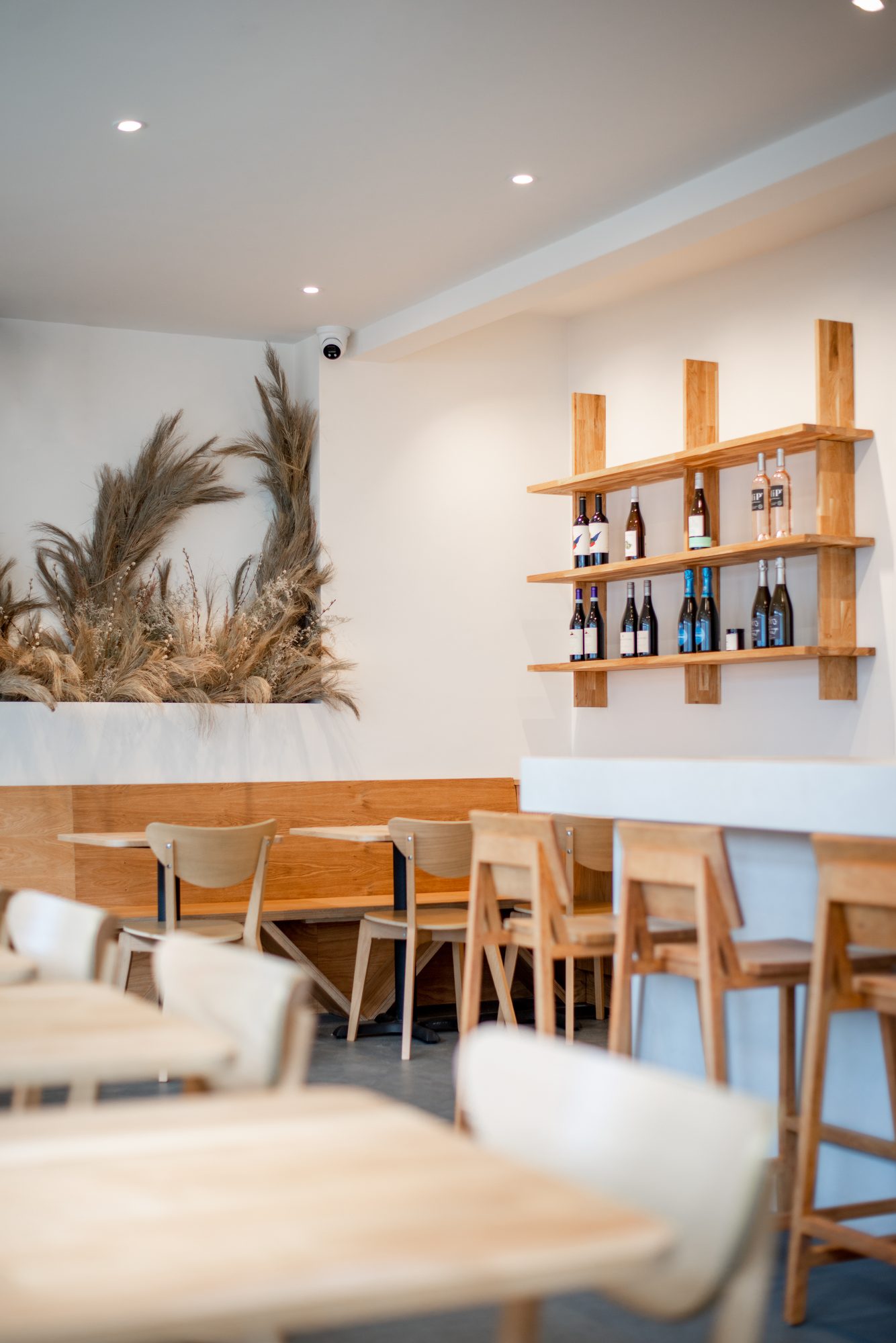 Dining area with pampas grass installation and oak wine shelves