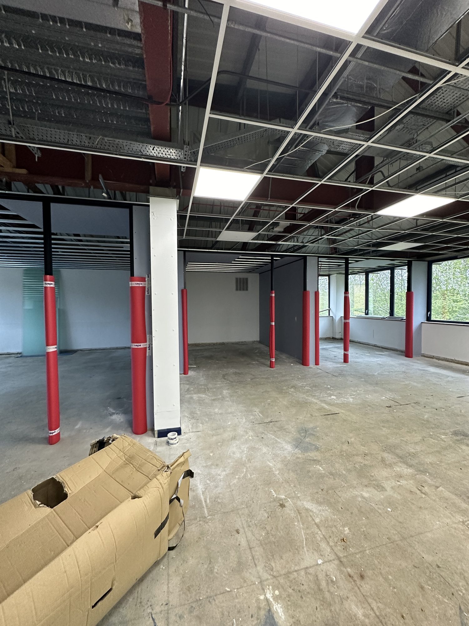 Early stage strip-out with red column protectors and open ceiling grid