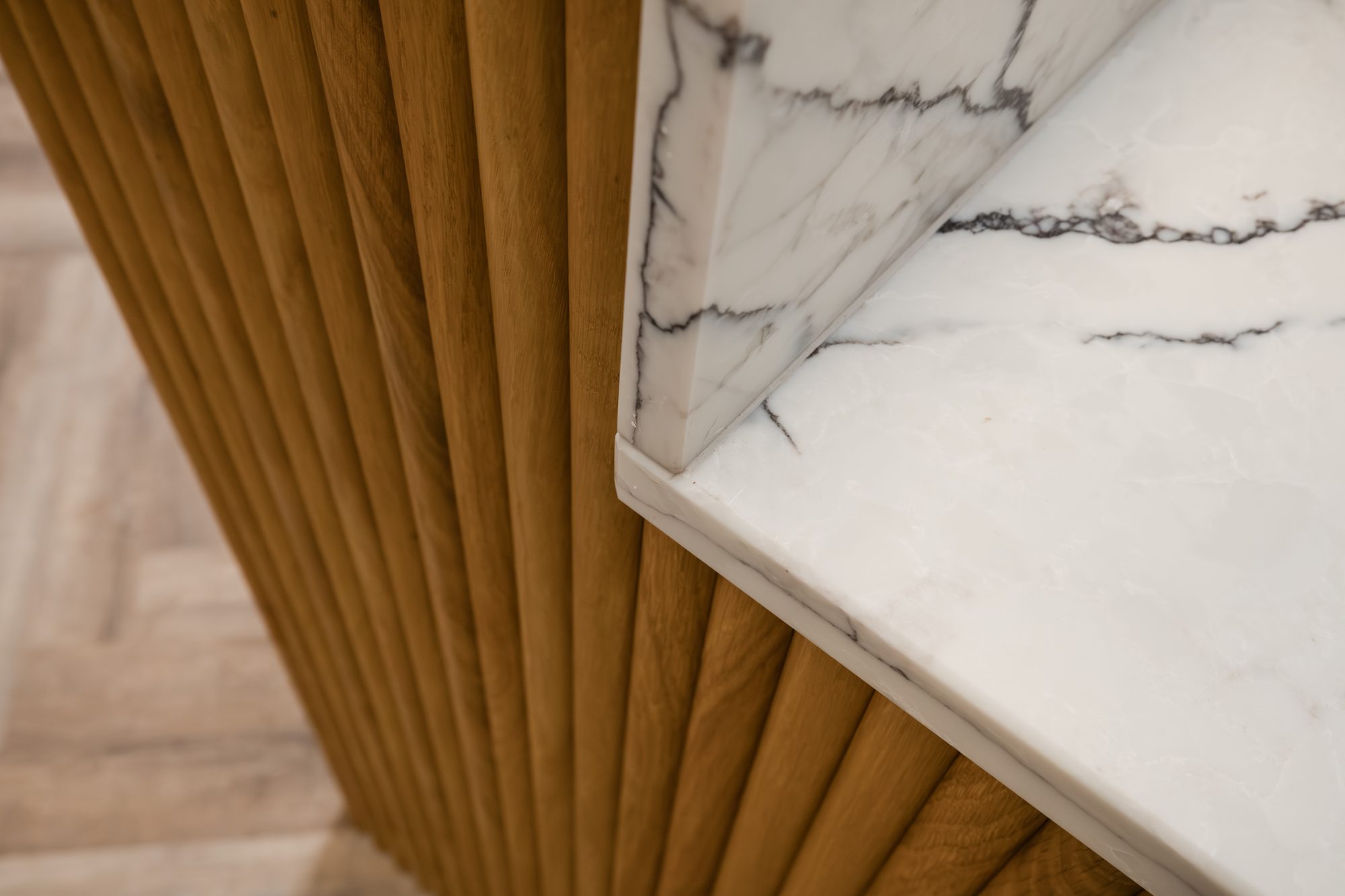 Close-up of fluted oak meeting marble waterfall edge, a detail of the bespoke kitchen
