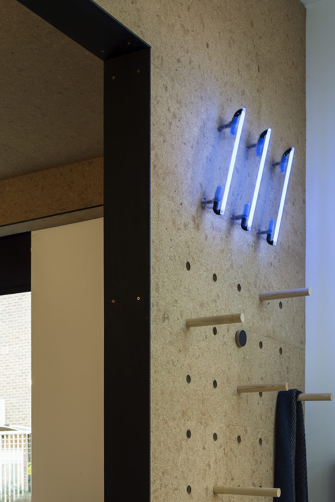 Detail of neon tube lighting on perforated MDF wall